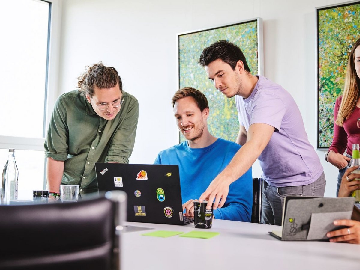 Drei lise-Entwickler arbeiten gemeinsam an einem neuen Projekt mit Hilfe eines Computers und Notizzetteln